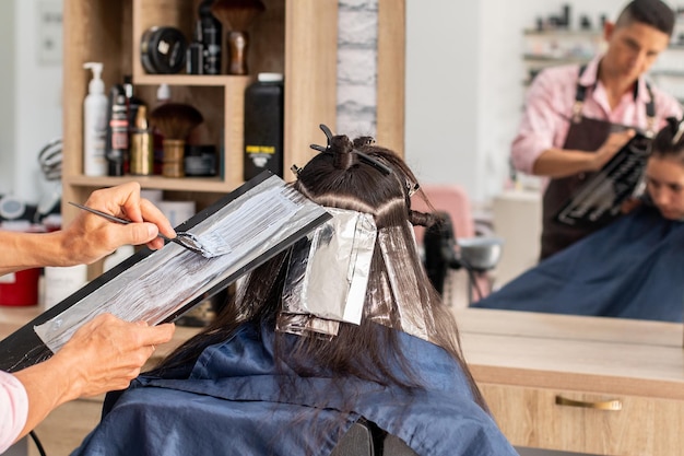 Professionele mannelijke stylist die het haar van zijn cliënt schildert Professionele schoonheidssalon