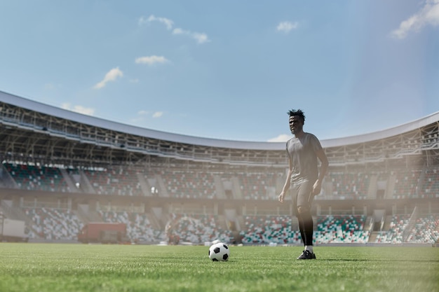 Professionele mannelijke voetbalvoetballer op stadionachtergrond Afrikaanse fitte atleet oefenen opgewonden spelen