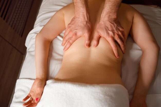 Professionele masseur maakt een therapeutische massage van de rug van de vrouw