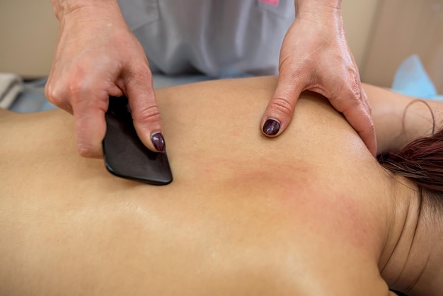Professionele masseurvrouw die steenmassage doet aan vaste klant