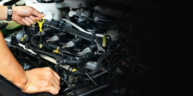 professionele monteur die de oliepeilstok vasthoudt, controleer het oliepeil in de motor van een auto