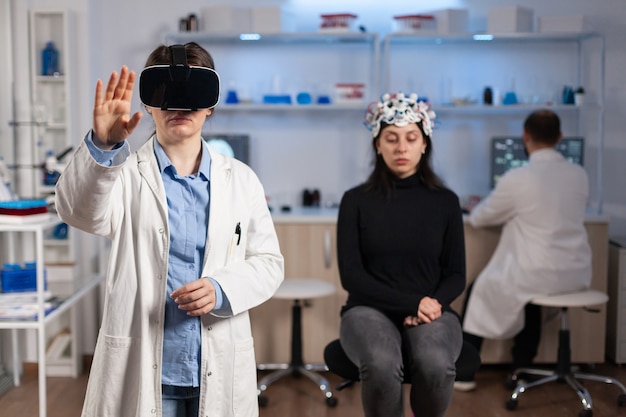 Professionele onderzoeker die een virtual reality-bril draagt met behulp van medische innovatie in het laboratorium dat de hersenscan van de patiënt analyseert. Team van neurologische artsen die werken met een high-tech simulatorapparaat voor apparatuur.
