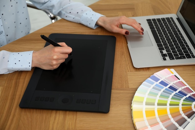 Professionele ontwerper met grafische tablet aan houten tafel close-up