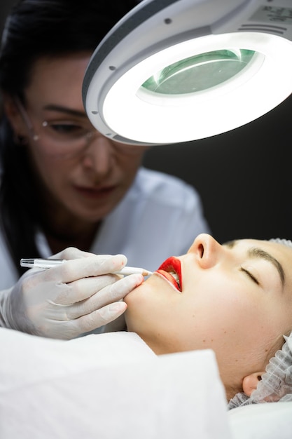 Professionele permanente make-up artiest en haar cliënt tijdens lip blush procedure