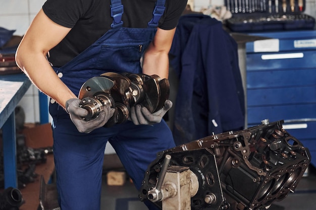 Professionele reparateur in garage werkt met kapotte automotor