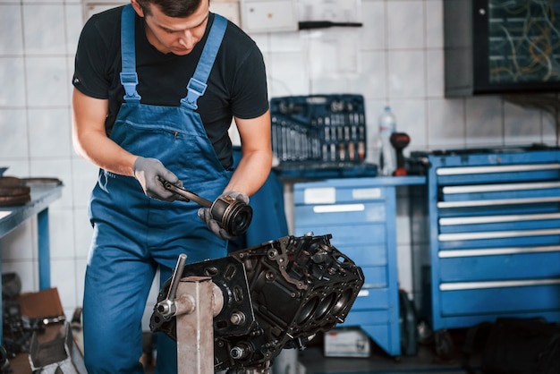 Professionele reparateur in garage werkt met kapotte automotor