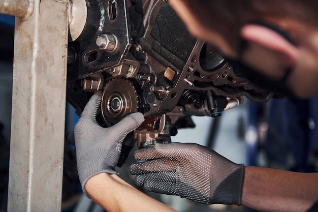 Professionele reparateur in zwart beschermend masker werkt met gebroken automotor