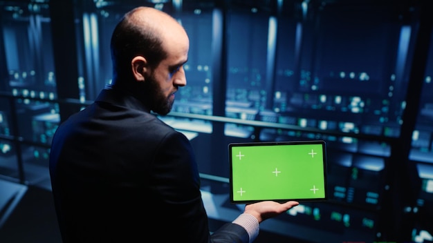 Professionele serveringenieur die greenscreen op tablet gebruikt en cloud computing in datacenter inspecteert. Ondersteuningsspecialist die naar lege copyspace en chroma key-sjabloon kijkt. Statief opname.