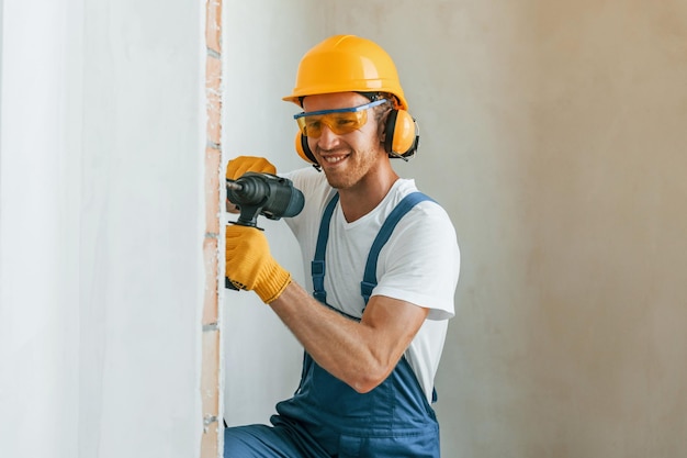 Professionele service Jonge man aan het werk in uniform bij de bouw overdag