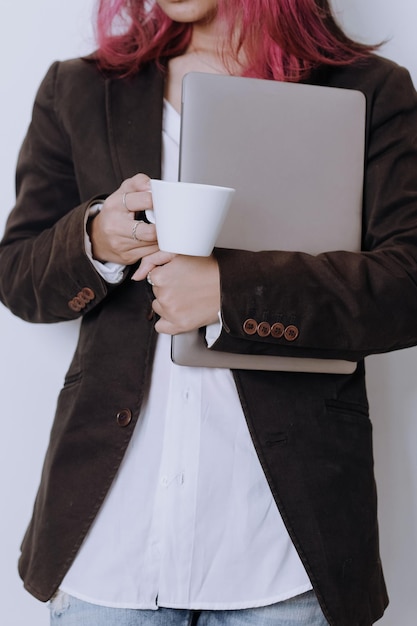 Professionele stijlvolle vrouw in pak houdt laptop en kopje koffie geïsoleerd op een witte achtergrond