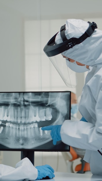 Professionele stomatoloog die tandenanimatie op het scherm bekijkt en model vergelijkt voor het gebit van de patiënt in de kliniek. Tandartsassistent die virtuele computertechnologie gebruikt voor bediening