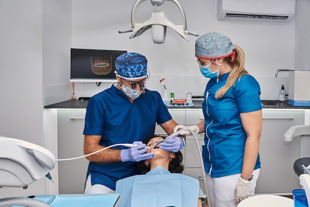 Professionele tandartsen onderzoeken de tanden van de vrouw in de tandartspraktijk.