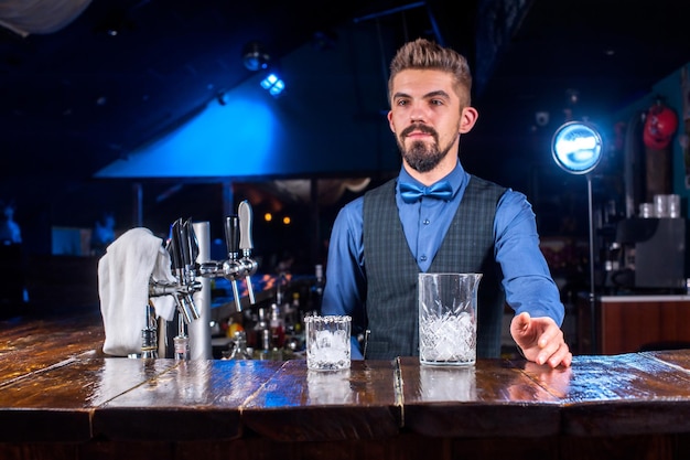 Professionele tapster die verse alcoholische drank in de glazen in de nachtclub giet