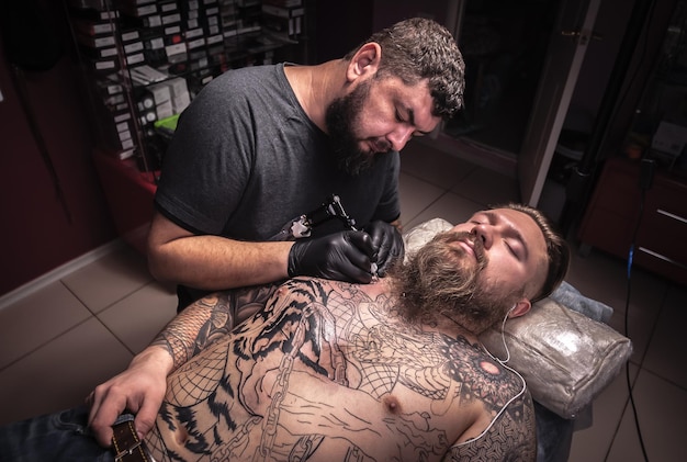 Professionele tatoeëerder aan het tatoeëren in tattoo salonTattooist die het proces van het maken van een tatoeage in tattoo salon laat zien