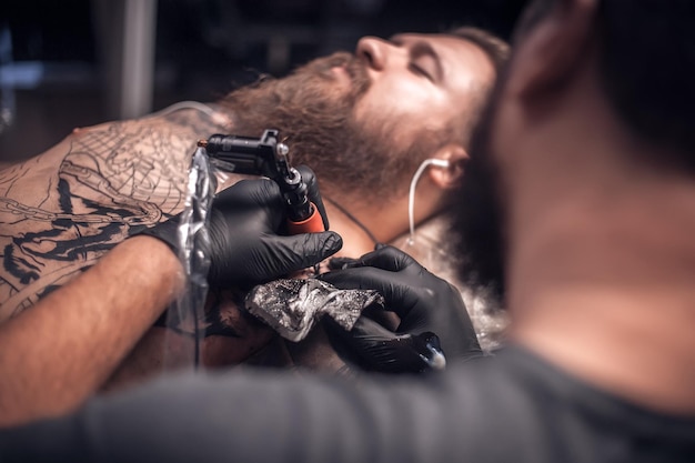 Professionele tatoeëerder die een tatoeage maakt in de studio Meester-tatoeëerder die een tatoeage doet in de tattoo-studio