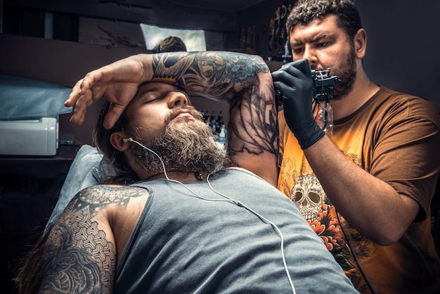 Foto professionele tatoeëerder poseren in tattoo studiomaster aan het werk in tattoo studio