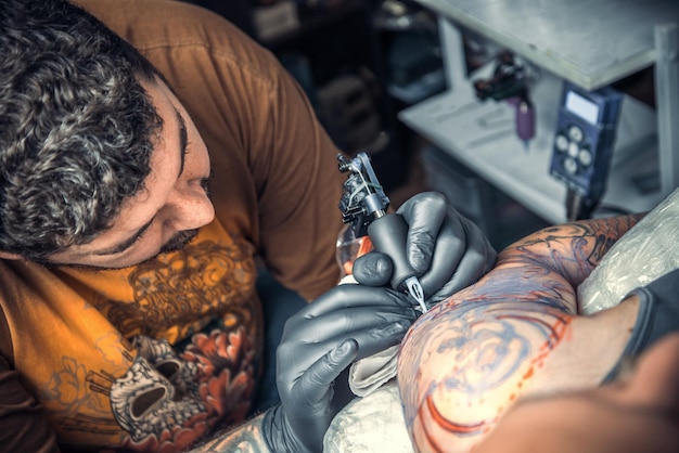 Professionele tatoeëerder werkt in tattooshop