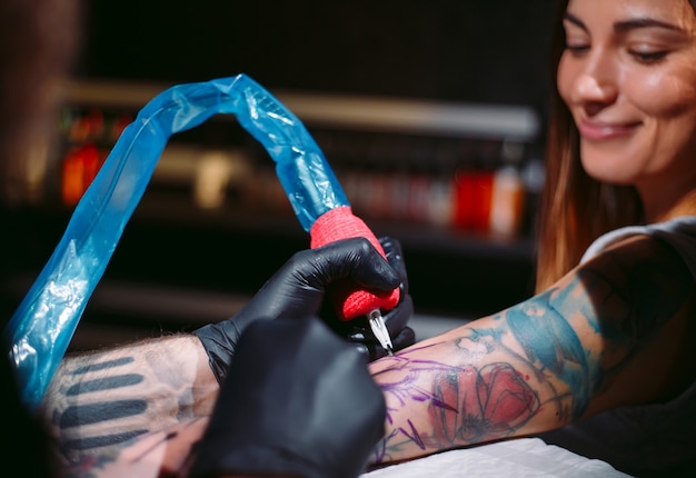 Professionele tattoo-artiest maakt een tatoeage op de hand van een jong meisje.