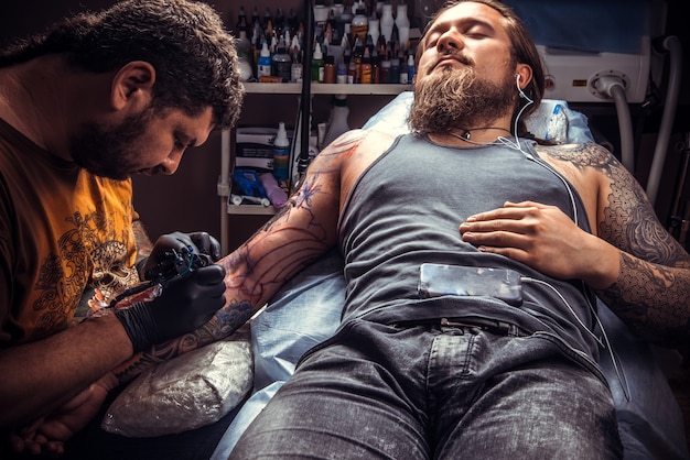 Professionele tattooer maakt coole tatoeages in tattoo-studio.