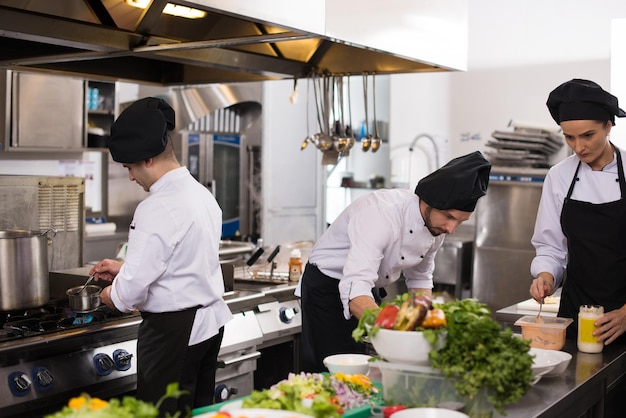 Professionele teamkoks en chef-koks die maaltijden bereiden in de drukke hotel- of restaurantkeuken