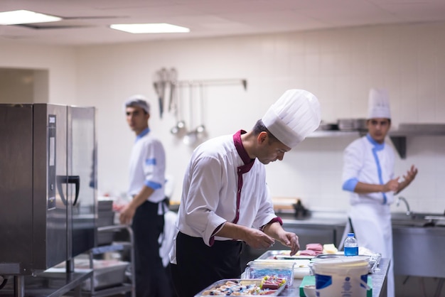 Foto professionele teamkoks en chef-koks die maaltijden bereiden in de drukke hotel- of restaurantkeuken