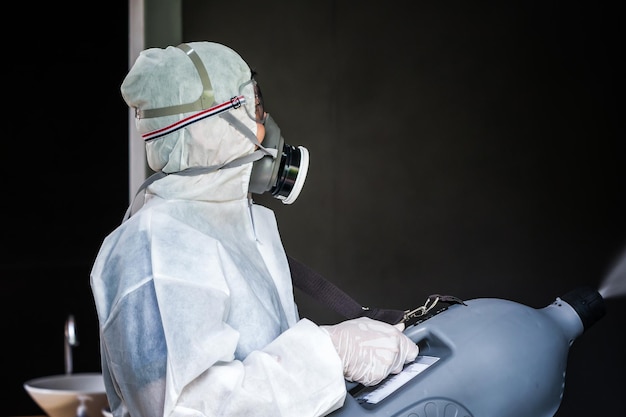 Professionele technische man in preventiepak met zijn sterilisatiemachine en desinfecterende watersprays in het buitenveld voor het zuiveren van coronavirus COVID19