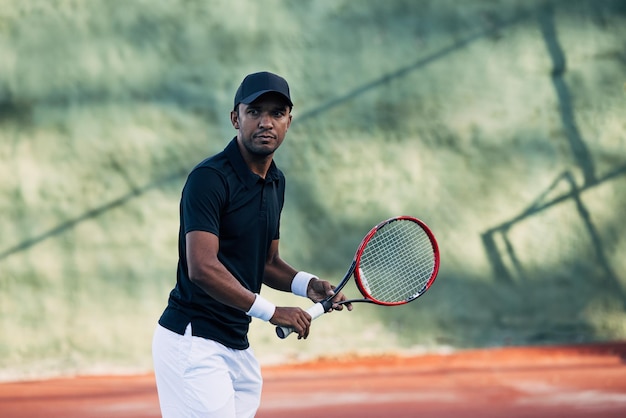 Professionele tennisspeler met racket kijkend naar camera op hardcourt