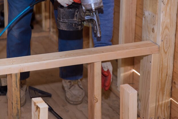 Professionele timmerman met luchtspijkerpistool pneumatische spijkermachine in de nieuwe woningbouw