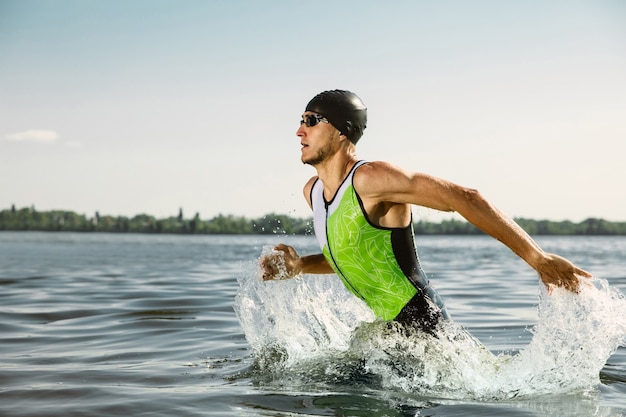 Foto professionele triatleet die in het open water van de rivier zwemt. man met zwemuitrusting die triatlon beoefent op het strand in de zomerdag. concept van gezonde levensstijl, sport, actie, beweging en beweging.
