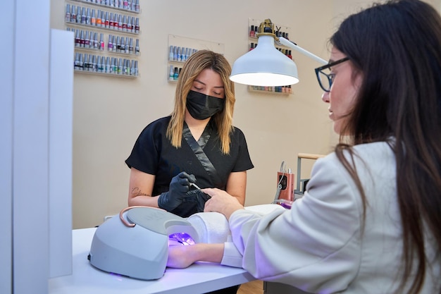 professionele van een schoonheidssalon die de nagels van een klant doet