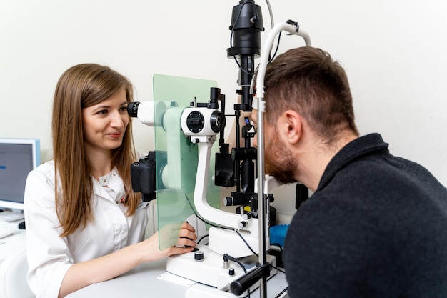 Foto professionele visiediagnose door jonge medisch specialist oogheelkundespecialist die de ogen van de patiënt onderzoekt