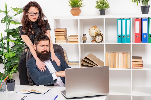 Professionele vrouw omarmen man aan het werk op laptop op kantoor werkplek romantiek