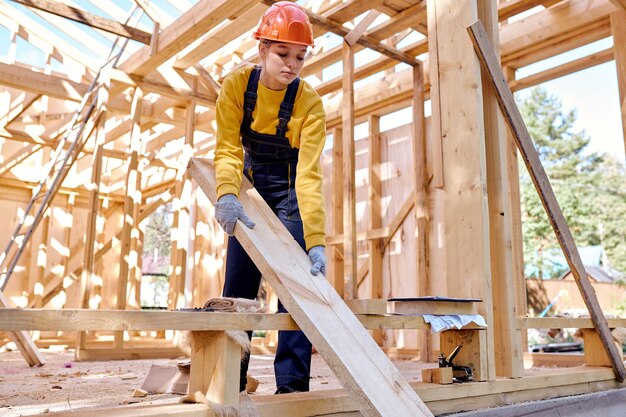 Professionele vrouwelijke constructeur die een helm draagt tijdens het voorbereiden van het frame