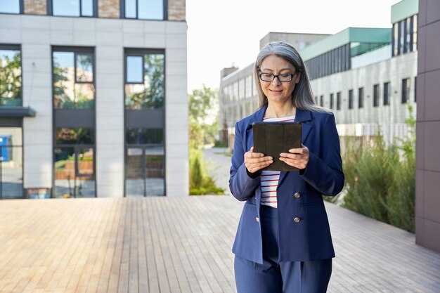 Professionele vrouwelijke kantoormedewerker die buiten staat met tablet