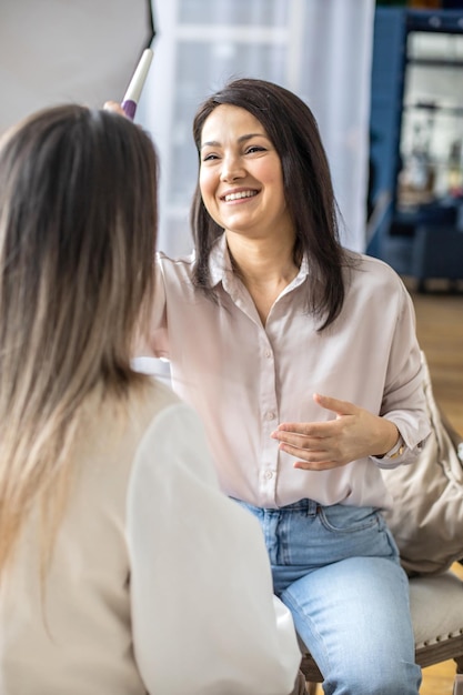 Professionele vrouwelijke make-upartiest die cosmetica aanbrengt op een modelgezicht, gebruik een borstel die werkt bij een schoonheidssalon