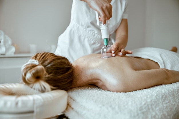 Professionele vrouwelijke specialist doet cupping-therapie op de rug van een mooie blanke dame