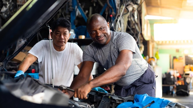 Professionele werktuigbouwkundig ingenieur Aziatische senior oude man en jonge man team werken onder auto bij auto