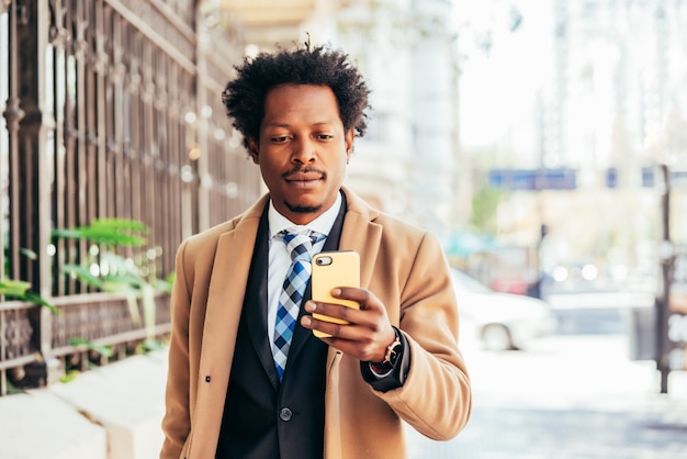 Professionele zakenman met behulp van zijn mobiele telefoon tijdens het wandelen om buiten te werken