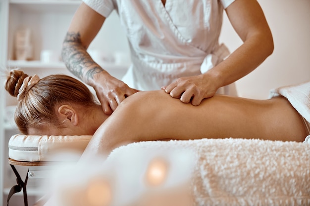 Professionele zelfverzekerde massagemeester doet procedures aan blanke vrouw in minimalistisch modern