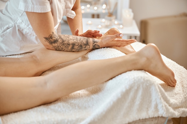 Professionele zelfverzekerde massagemeester doet procedures aan blanke vrouw in minimalistisch modern