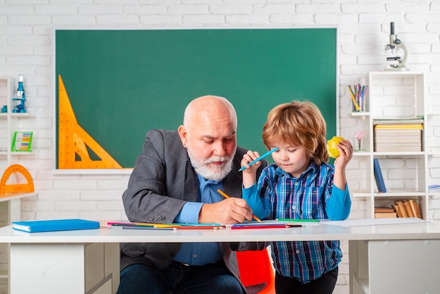 Professor and pupil in classroom at the elementary school child at school lesson with senior teacher