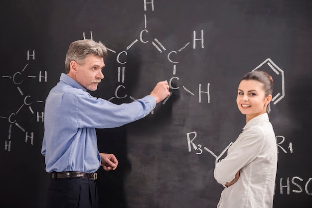 Il professore e la donna scrivono insieme sulla formula della lavagna.