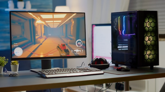 Professsional gaming empty room studio with neon lights and RGB powerful computer, keyboard and mouse. FPS shooter video game on pc display, stream chat on television