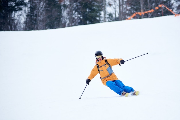 Proficient young skier concentrated on skiing down on steep ski slope