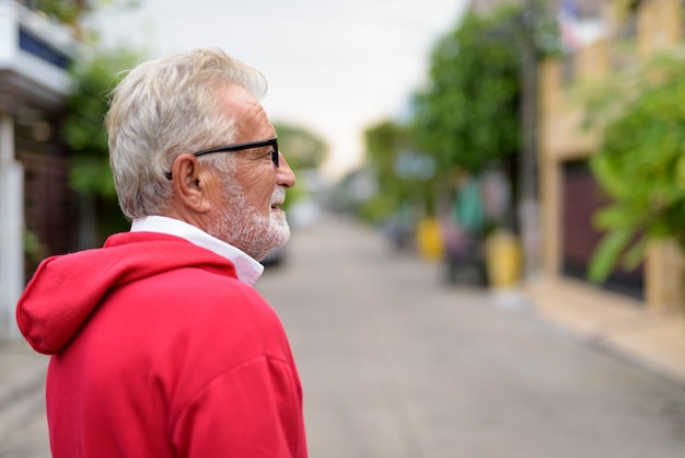 Profiel te bekijken van gelukkig knappe senior bebaarde man die lacht terwijl het dragen van een bril buitenshuis