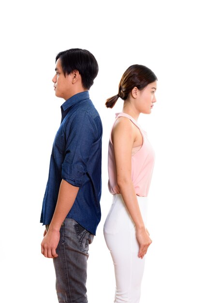 Profiel te bekijken van jonge aziatische paar met rug tegen elkaar geïsoleerd