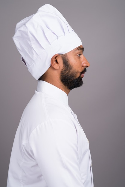 Profiel te bekijken van jonge Indiase man chef-kok op grijze achtergrond