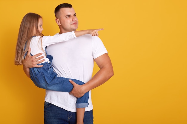 Profiel te bekijken van jonge vader zijn dochtertje knuffelen en wegkijken,