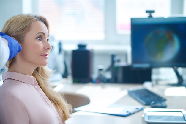 Foto profiel van een vrouw die zit op een afspraak met een otolaryngoloog