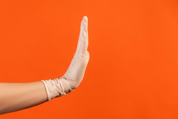 Profiel zijaanzicht close-up van menselijke hand in witte chirurgische handschoenen die stop met hand tonen.